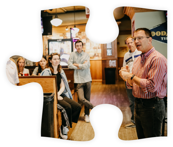 Puzzle piece with a photo of MSI Data employees gathered at a restaurant, listening to a speech.