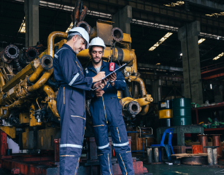 Two field technicians working in a warehouse, standing together.
